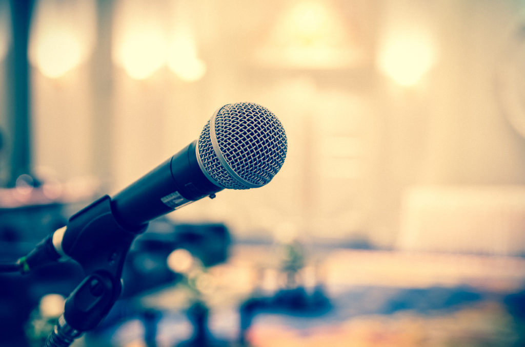 Microphone over the Abstract blurred photo of conference hall or seminar room background